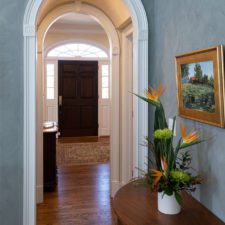 Entryway with arched doorways and blue wallpaper.